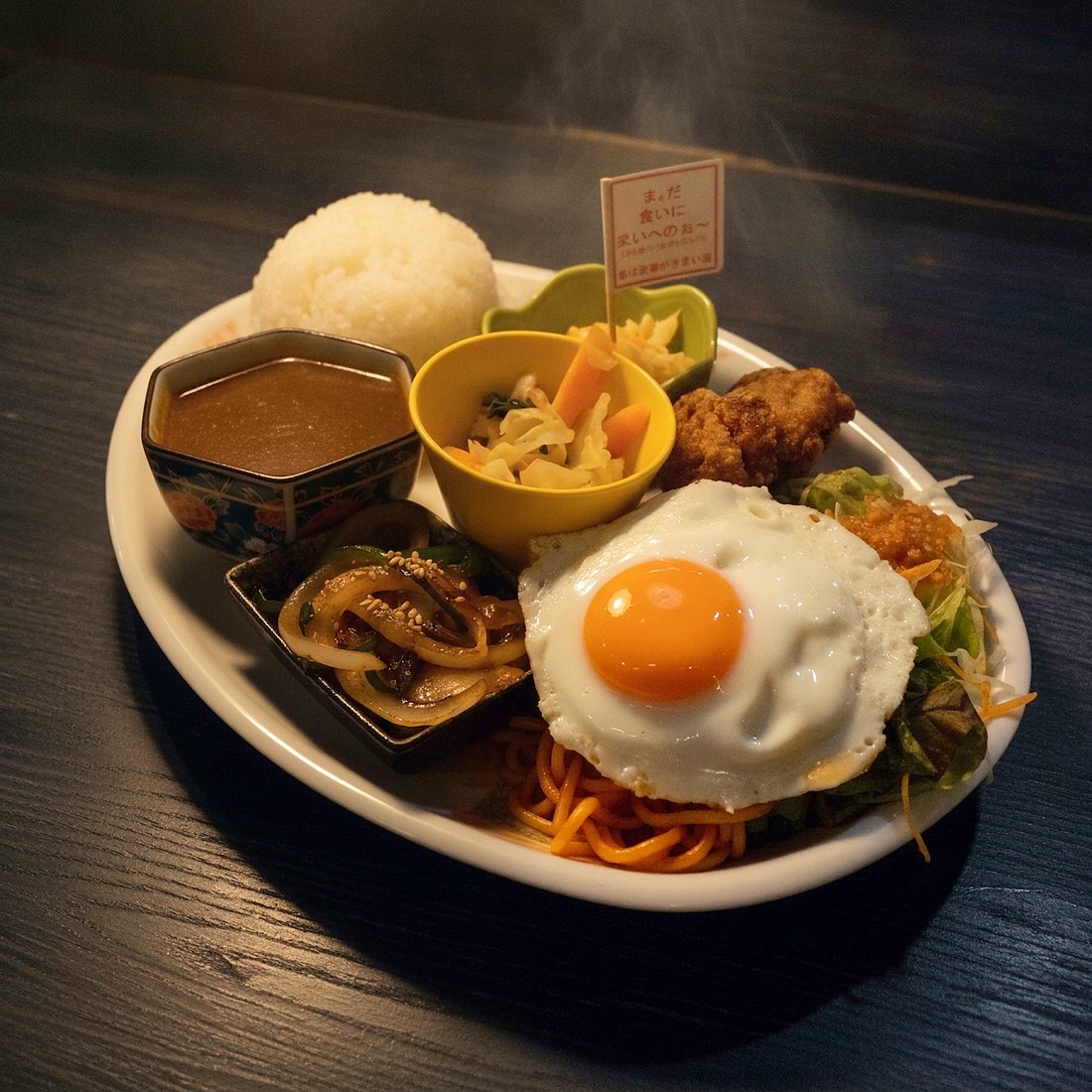 大人用子供プレート — 白い楕円皿にナポリタンと目玉焼き、唐揚げ、生姜焼き、ごはん、カレー、サラダ、小鉢、津軽弁の旗